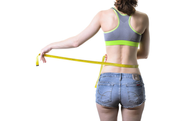 Стройная молодая женщина измеряет себя измерительной лентой, изолом
 - Фото, изображение
