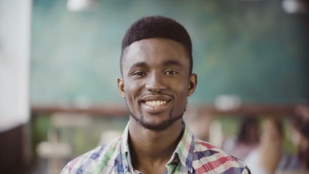 Portrait of young successful African businessman at busy office. Handsome male looking at camera and start smiling. - Filmagem, Vídeo
