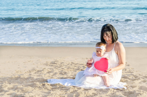 Mutter mit Tochter und Herz am Sandstrand  - Foto, Bild
