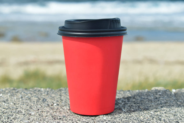 Paper cup of coffee on the background of the sea on the stones - Foto, Imagen
