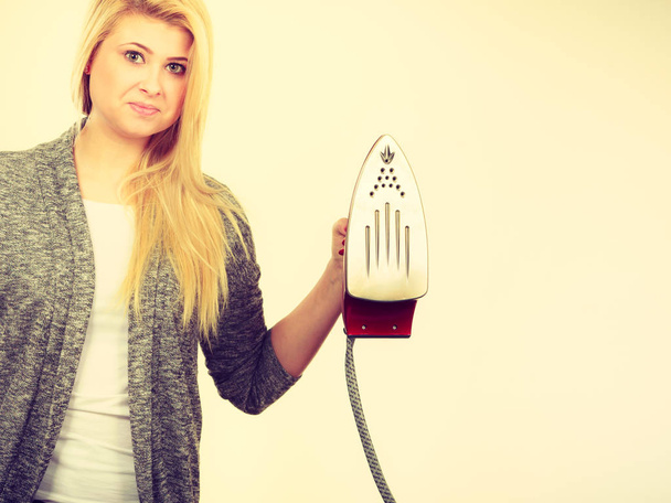 Woman holding iron about to do ironing - Foto, Bild