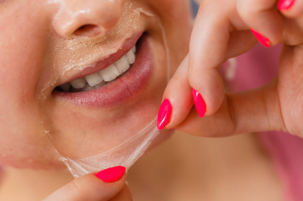 Woman peeling off gel mask from face - Photo, Image