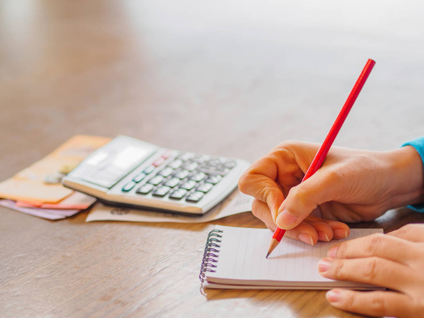 Mujer usando calculadora y pensando en el costo en el escritorio en la oficina en casa
. - Foto, imagen