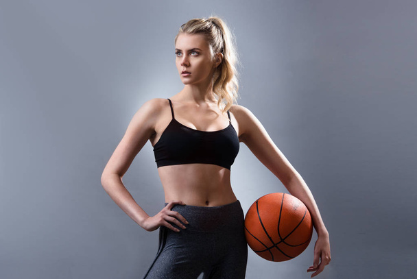 Beautiful woman basketball player standing and holding basketball ball - Foto, Imagem