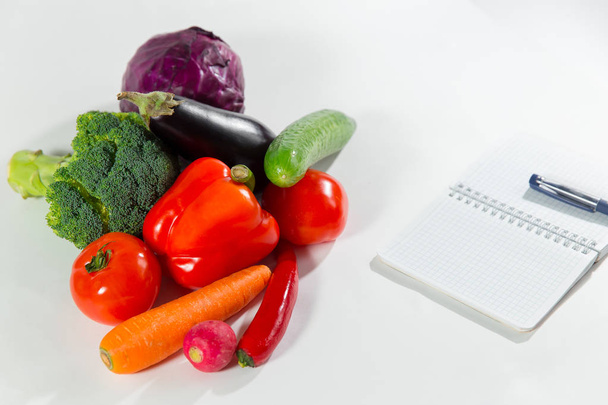 Fresh vegetable collection and notebook with diet plan isolated on white background. - 写真・画像