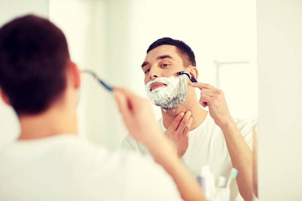 homme rasage barbe avec lame de rasoir à la salle de bain
 - Photo, image