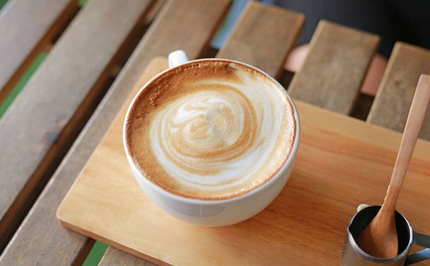 Top view hot latte coffee with hearts pattern and syrup on wooden table - 写真・画像