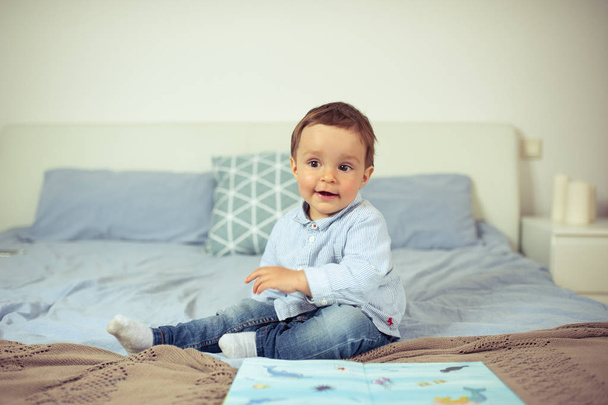Kisfiú játszik az ágyon. Egy boldog kis gyerek. - Fotó, kép