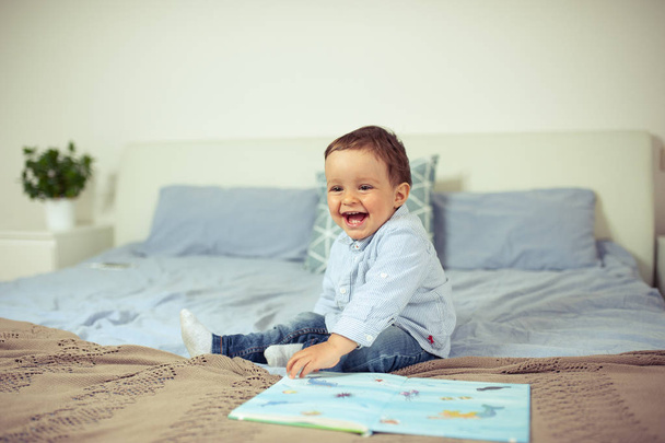 Μικρό αγόρι παίζει στο κρεβάτι. Ένα ευτυχισμένο παιδάκι. - Φωτογραφία, εικόνα