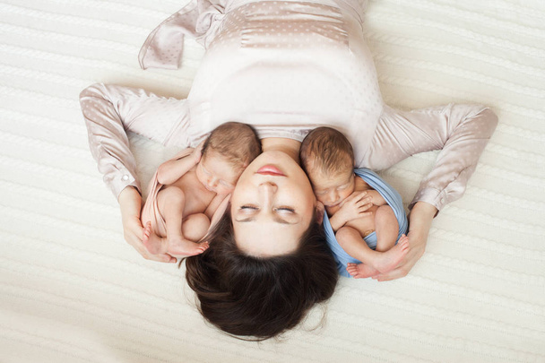 мати лежить з новонародженою дівчиною і хлопчиком
 - Фото, зображення