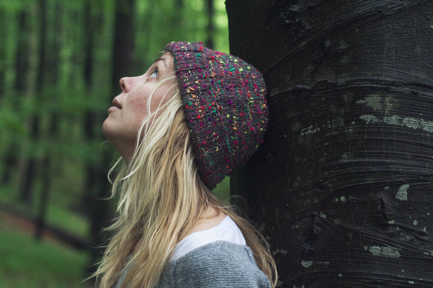 Nuori nainen vihreässä metsässä katselee ylös
 - Valokuva, kuva