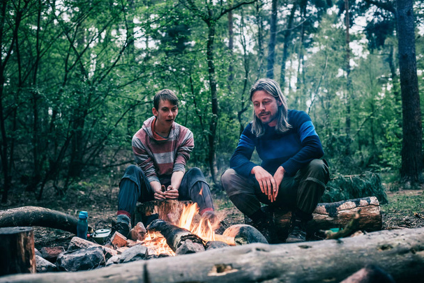 Two men sitting around campfire  - Foto, imagen