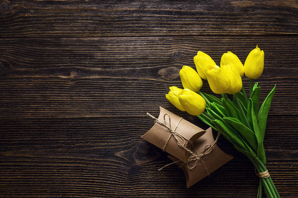 Букет желтых тюльпанов с подарочными коробками на темной деревянной бэкгро
 - Фото, изображение