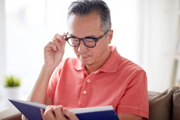 man in glasses reading book at home - Foto, Imagen