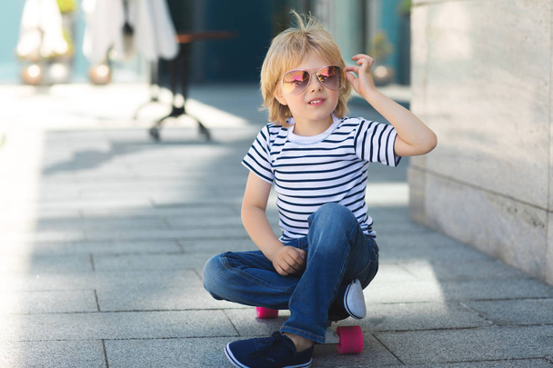 Pretty little boy on a skate board. Emotional kid outdoors. Cute - Photo, Image