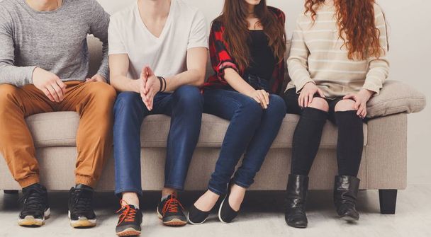 Crop of young friends sitting on couch indoors - Photo, Image