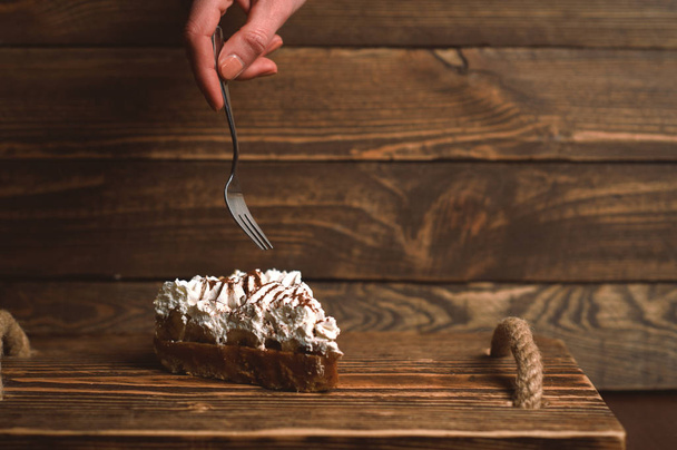 hand with fork and cake on wooden desk - Foto, Bild