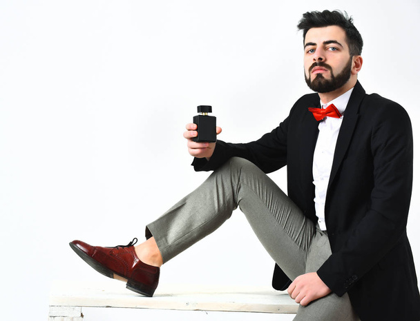 Bearded man, caucasian hipster with moustache holding perfume bottle - Fotó, kép