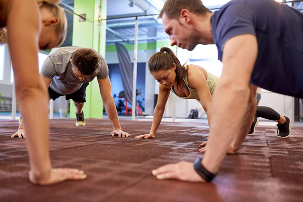 group of people doing straight arm plank in gym - Zdjęcie, obraz
