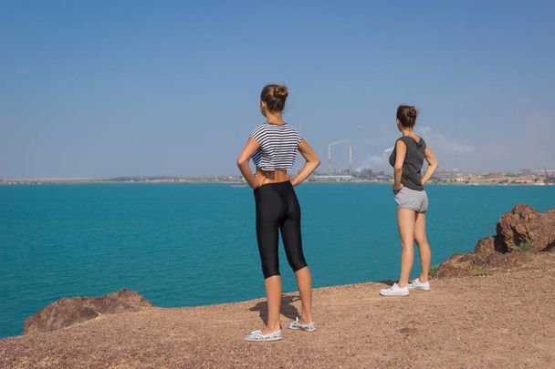 Two girls are doing yoga meditation on the beach. The concept of sports and healthy lifestyle. Summer holidays - Photo, Image