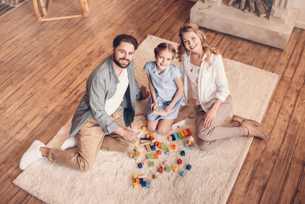 gelukkig gezin spelen met constructor en zittend op de vloer thuis - Foto, afbeelding