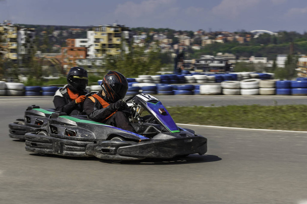 Karting Championship. Driver in karts wearing helmet, racing suit participate in kart race. Karting show. Children, adult racers karting. - Photo, Image