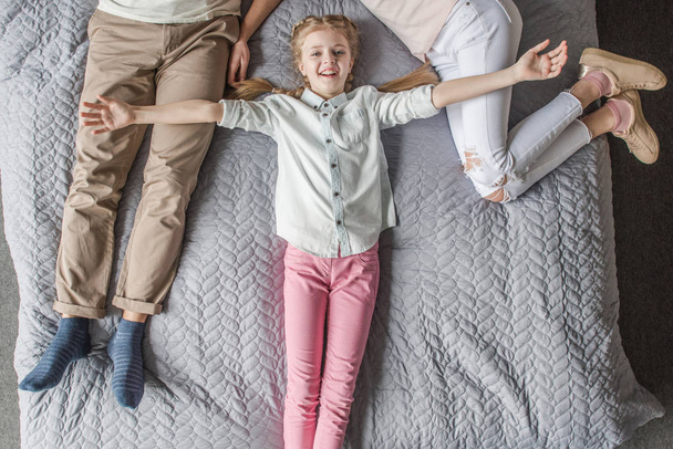heureuse adorable fille avec mère et père se détendre sur le lit à la maison
 - Photo, image
