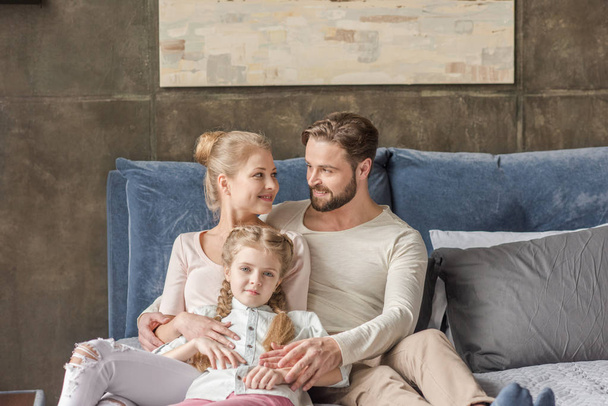 Happy mother, father and daughter hugging and smiling at home - Valokuva, kuva