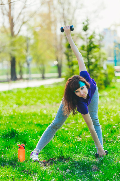 Menina fitness no parque e envolvidos em vários exercícios com haltere e tapete. morena vai para esportes ao ar livre
 - Foto, Imagem