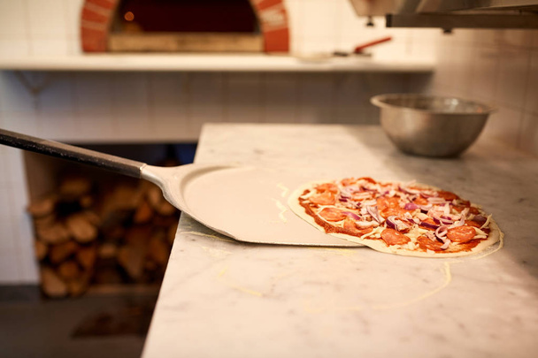 peel taking pizza off table at pizzeria - Foto, Bild