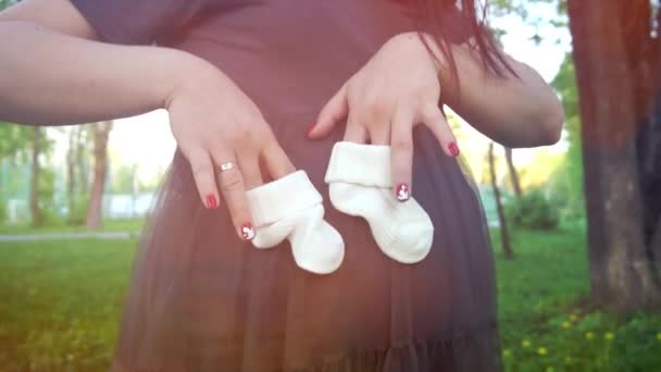 Gelukkig zwangere jongedame spelen met baby laarsjes op haar zwangere buik - Video