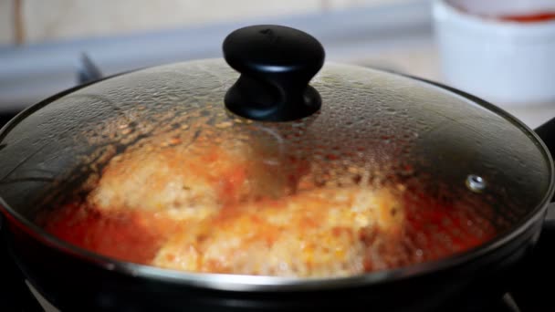 Uma mulher cozinha frango com molho de tomate. Mão aberta pan tampa
. - Filmagem, Vídeo