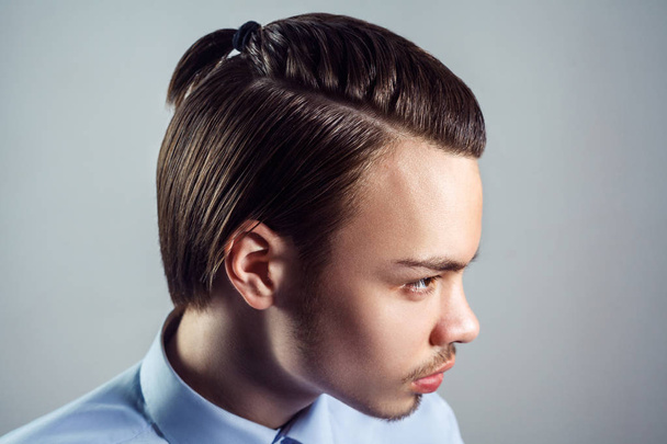 Side view portrait of young man with top knot hairstyle. studio shot. - 写真・画像