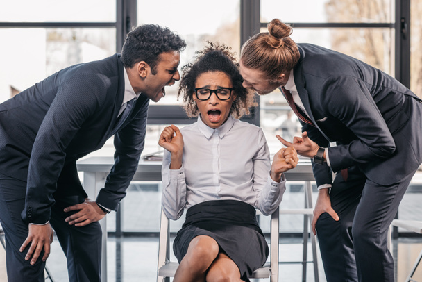 zakenlieden schreeuwen op zakenvrouw in kantoor - Foto, afbeelding