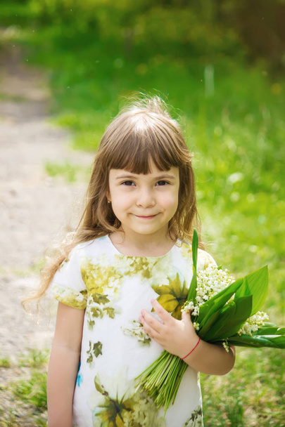 Girl with a bouquet of lilies of the valley. Selective focus. - Photo, Image