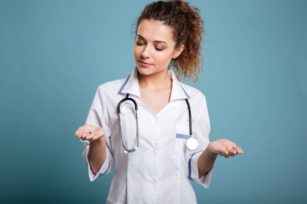 Nurse woman making choice between pills in her hand - Foto, Imagen