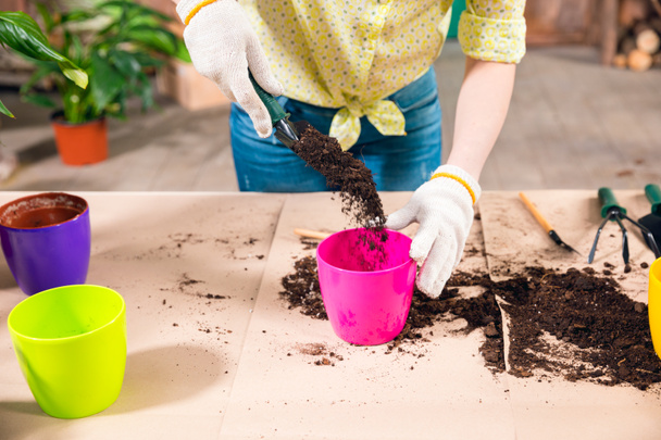 cropped view of woman with shovel, soil, flowerpots and plant on table - Фото, зображення