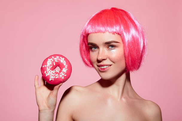 woman with pink hair holding doughnut - Foto, Imagen