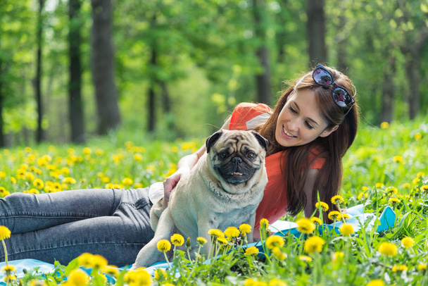 Dog of the Pug breed. A girl is walking a dog on a green lawn. - Zdjęcie, obraz