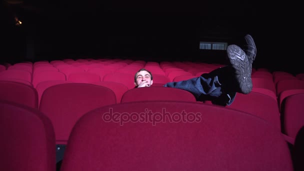 One man sitting in comfortable red chairs in dark cinema theater Looks comedy and laughs - Footage, Video