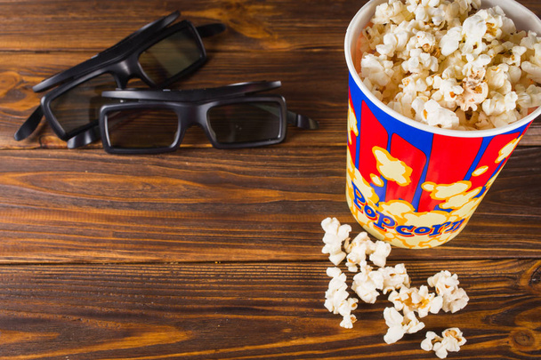 popcorn and glasses on a wooden background. - Фото, зображення