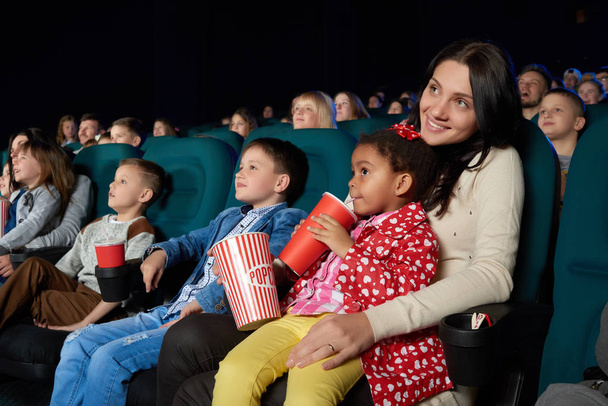 Children with parents enjoying a movie together at the cinema - Photo, Image