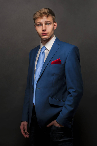 Young handsome man in blue suit smiling on dark background - Photo, Image
