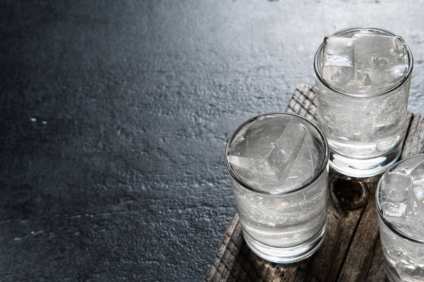 Vodka sulle rocce su un vecchio tavolo di legno come dettagliate riprese ravvicinate
 - Foto, immagini