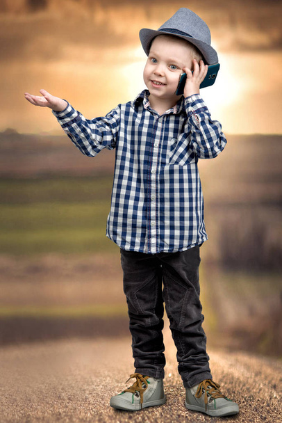 A little boy in a hat talks on his mobile phone.Little boss . - Foto, Imagen