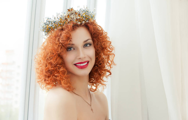 Happy bride. Beautiful red head curly woman with crown fashion model person girl looking at you camera smiling at boyfriend groom isolated  near window indoor white curtains background. Miss sunshine - Foto, Imagem