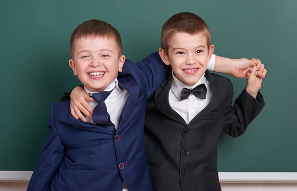 two friends, elementary school boy near blank chalkboard background, dressed in classic black suit, group pupil, education concept - Photo, Image