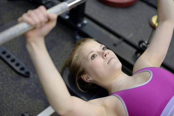 vrouw tillen gewichten in gym - Foto, afbeelding