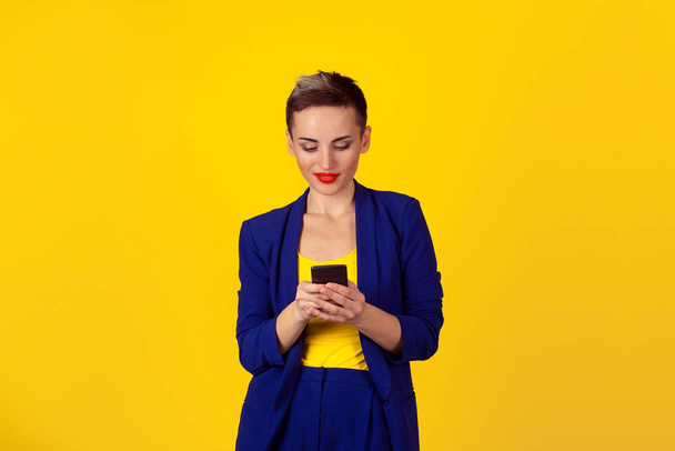 Happy young woman holding using new smartphone connected browsing internet worldwide isolated on yellow wall background. 4g data plan provider - Zdjęcie, obraz