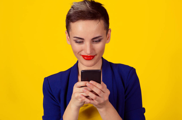 Retrato de jovem mulher de negócios feliz mensagens de texto no telefone inteligente isolado parede de fundo amarelo
 - Foto, Imagem